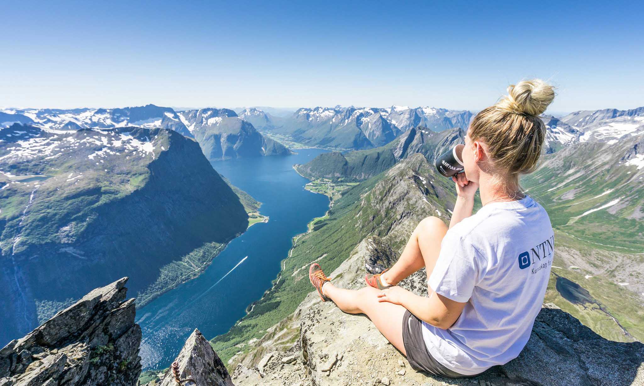 Woman drinking from a cup on top of a mountain