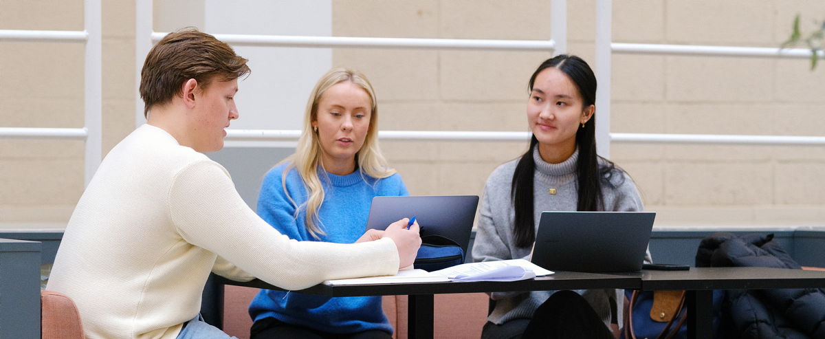 Three students having a conversation indoor, at a table